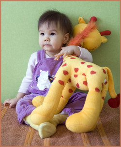 baby sitting on floor holding a stuffed giraffe